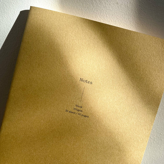 A plain brown notebook with the word 'Notes' printed on the cover