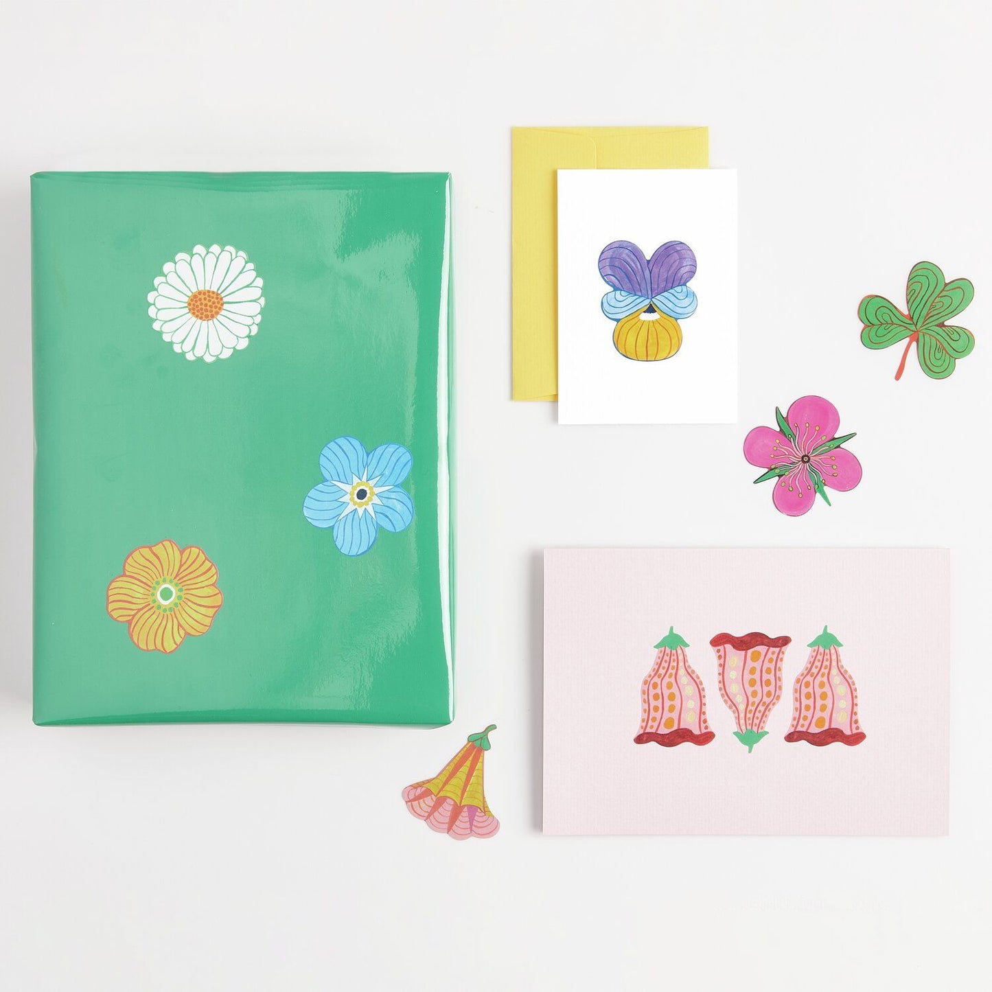 A selection of colorful floral stickers on a green notebook and cards from the Pencil Me In stationery shop.