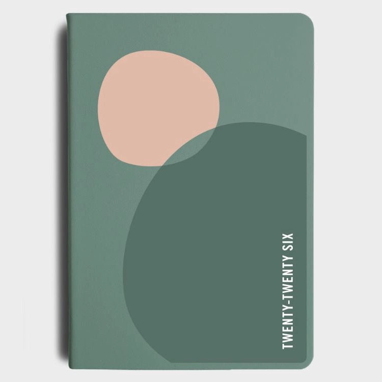 Green diary with a pink circle and 'TWENTY-TWENTY SIX' text on a light gray background