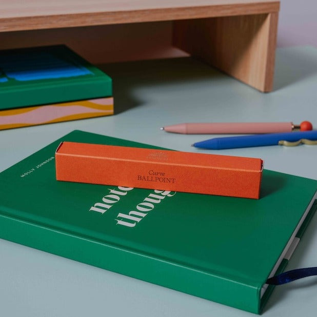 An orange pen box from the Pencil Me In stationery shop.
