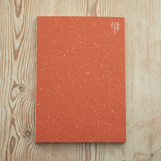 A orange notebook with plain paper from the Pencil Me In stationery shop. 