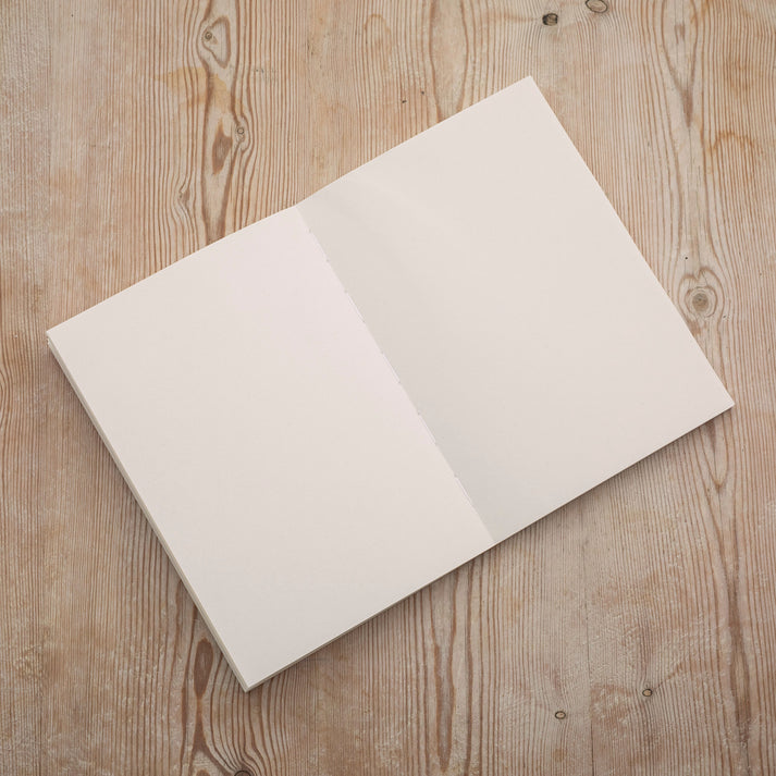 An open plain paper notebook from the Pencil Me In stationery shop.